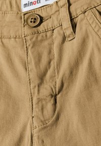 Kaki bomullsshorts med en stickad framficka, en brun knappstängning och en märkesetikett i midjan. Slät textur, avslappnad design.