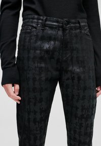 Svarta mönstrade byxor med en slät textur och subtil lyster, med en figurnära design, bältesöglor och framfickor.