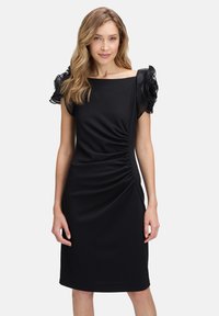 Schwarzes Kleid mit kurzen, gerafften Ärmeln, tailliertem Schnitt und seitlicher Raffung zur Formgebung, aus einem weichen, elastischen Material gefertigt.