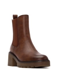 Stivale alla caviglia marrone realizzato in morbida pelle sintetica, con pannelli laterali elasticizzati, un tacco spesso e una suola in gomma testurizzata con scanalature.