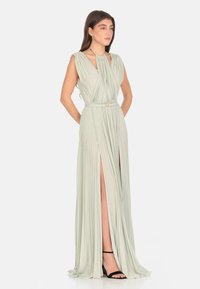 Abito maxi plissettato verde chiaro con spacco alto, design senza maniche e scollatura arricciata. Presenta una vita cinturata e una trama liscia.