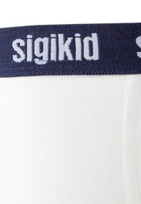 White cotton garment with a dark blue elastic waistband, featuring the brand name "sigikid" in light blue embroidery. Smooth texture.