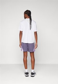 Witte overhemd met korte mouwen en een subtiele yawke-design, gecombineerd met paarse sportshorts met lichte paarse accenten en een relaxte pasvorm.