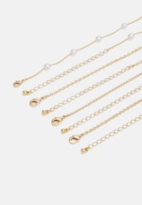 Gold jewelry chains of varying lengths with a pearl accent. Chains feature lobster clasps and small spherical details, smooth texture.