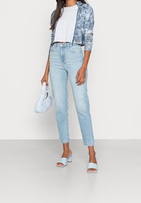 Ljusblå tie-dye jacka, vit kortärmad t-shirt, ljusblå jeans, mintgröna klacksandaler och en liten ljusblå handväska.