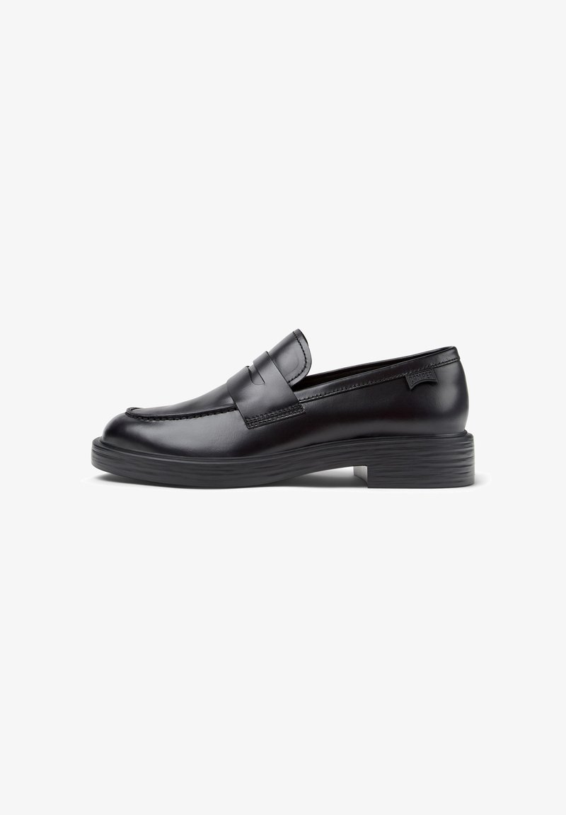 Black leather loafer with a low ribbed heel, rounded toe, decorative stitched accents, and a front strap detail. Smooth texture.