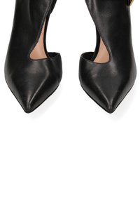 Scarpe nere in pelle con tacco alto, punta affusolata e disegno a taglio sui lati. Texture liscia e stile minimalista, senza parti metalliche visibili.
