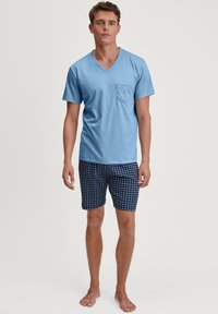 Lichtblauw V-hals T-shirt met een borstzak, gecombineerd met marineblauwe short met een geometrisch patroon, gemaakt van zachte stof.