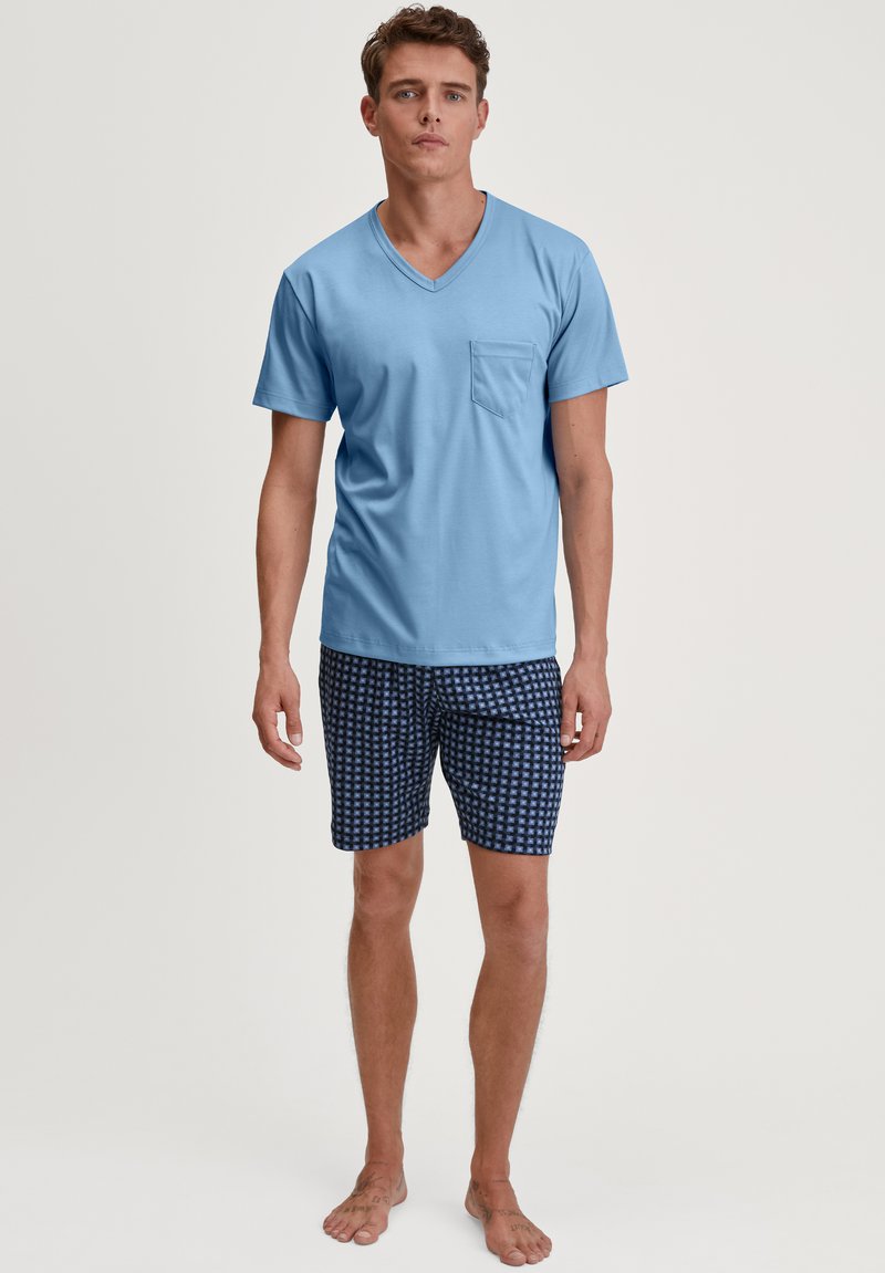 Lichtblauw V-hals T-shirt met een borstzak, gecombineerd met marineblauwe short met een geometrisch patroon, gemaakt van zachte stof.
