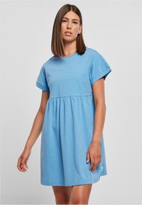 Mėlynas medvilninis t-shirt suknelė su trumpomis sukištomis rankovėmis, surinkta juosmens linija ir laisvu siluetu. Yra mažas logotipo ženkliukas prie apatinio krašto.