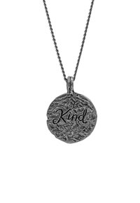 Silverfärgad berlock på en snoad kedja, rund form med texturerad yta, graverad med ordet "Snäll" i ett kursivt typsnitt.