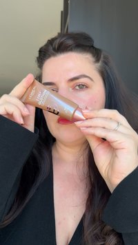 L'Oréal Paris Lumi Glotion in einer braunen Tube mit metallic Oberfläche. Die Verpackung hat ein kreisförmiges Design, das mit Produktdetails beschriftet ist.