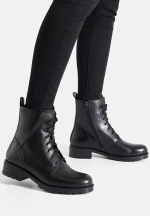 Czarne skórzane botki za kostkę z przednim sznurowaniem, bocznym zamkiem błyskawicznym, szerokim obcasem i teksturowaną podeszwą. Gładkie wykończenie z małą metką z logo z tyłu.