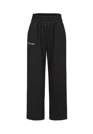 Zwarte, elastische sweatpants met een losse pasvorm en zijzakken. Heeft de tekst "Sports Club" in witte borduursel op de linker dij.