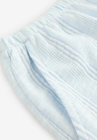 Tessuto a trama leggera di colore azzurro con strisce testurizzate e delicate pieghe. Presenta una vita elastica per una vestibilità regolabile.
