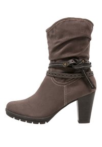 Bota al tobillo de ante marrón con parte superior holgada, correa de cuero negra con detalles metálicos y tacón apilado. Suela texturizada para mayor agarre.