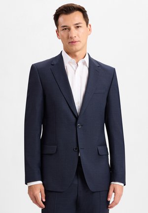 Mørkeblå jakkesætjakke med flapkraver, to frontlommer og enkelt knaplukning, parret med en hvid skjorte med krave.