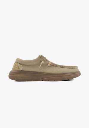 Beige instappers met een suède-achtige textuur, voorzien van een tan accenthiel, gestikte details en een flexibele rubberen zool.