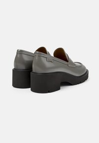 Scarpe in pelle grigia con punta arrotondata, dotate di una robusta suola a piattaforma nera e dettagli di cucitura discreti. Logo del marchio sulla parte posteriore.