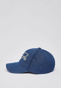 Casquette de baseball en denim bleu avec une visière incurvée, ornée d'un logo décoratif brodé en blanc à l'avant et d'un bouton supérieur cousu.