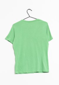 Grøn bomulds T-shirt med rund hals og korte ærmer, der har en glat tekstur og et simpelt design, hængende på en sort krog.