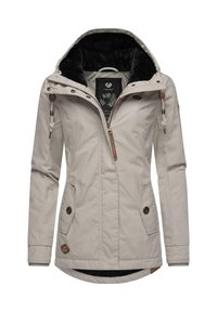 Beige waterproof jacket with a black fleece-lined hood, zip closure, two front pockets, and decorative hardware accents.