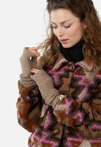 Cappotto di lana a motivo marrone e rosa con colletto, chiusure a bottoni e maniche aderenti. Guanti senza dita in lana completano l'outfit.