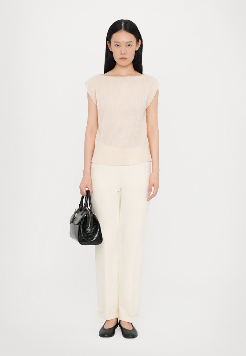 Cream ribbed short-sleeve top, paired with cream wide-leg trousers. Black structured handbag and black flats complete the look.