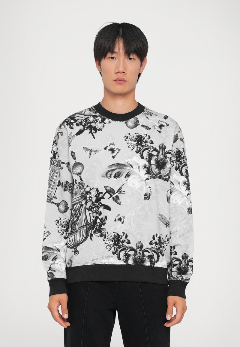 Μαύρο και λευκό πουλόβερ με σχέδια λουλουδιών και πεταλούδων, ριμπ μανίκια σε μαύρο χρώμα και στρογγυλή λαιμόκοψη σε ανοιχτό φόντο.