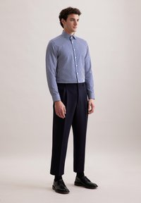 Blauw-wit gestreept overhemd met een standaard kraag, gecombineerd met op maat gemaakte zwarte broek en zwarte leren schoenen.