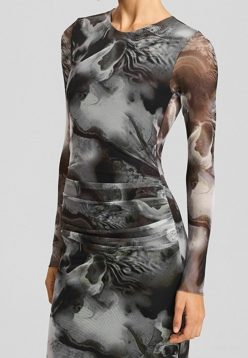 Robe longue ajustée à manches longues avec des motifs abstraits noirs, gris et marron imitant le marbre et des détails froncés à la taille.