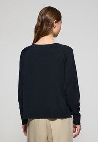 Ciemnoniebieski sweter dzianinowy o luźnym kroju, z raglanowymi rękawami oraz ściągaczami na mankietach i dole. Gładka tekstura bez widocznych wzorów lub ozdób.