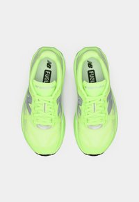 Par neonsko zelene New Balance FuelCell Rebel trkačke cipele prikazane odozgo na bijeloj pozadini.