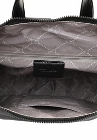 Interior de bolso negro con un bolsillo con cremallera y un forro gris estampado con textura acolchada. Acentuado con una etiqueta negra.