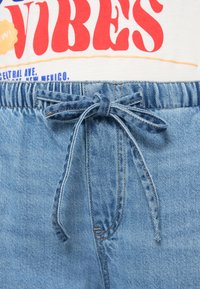 Shorts en denim avec une teinte bleu clair, dotés d'une taille élastique avec un nœud noué et une finition douce et texturée.