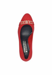 Röd mocka-pumps med spetsig tå, med en goldtonad logotypdetalj och svart innertyg. Slen yta, elegant design.