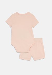Lys rosa kortermet bodysuit med rund hals, kombinert med matchende shorts med elastisk midje. Mykt bomullsmateriale, glatt tekstur.