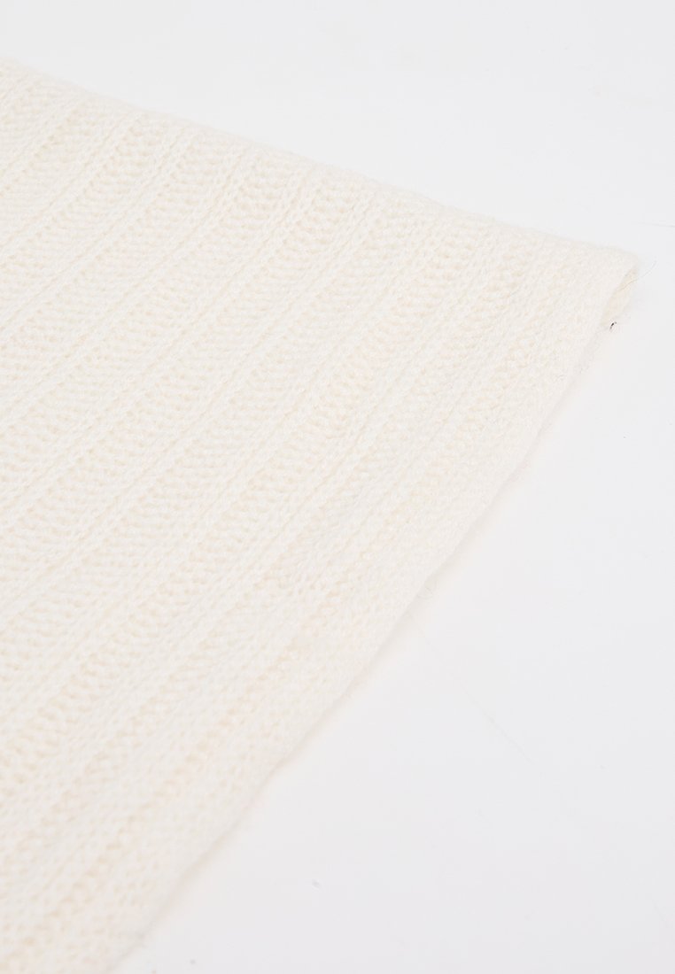 Strickdecke in cremigem Weiß, mit einem strukturierten Design und horizontalen Rippungen. Weiches, flexibles Material mit einer warmen Ausstrahlung.