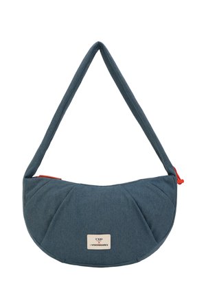 Sac d'épaule en tissu bleu en forme de croissant, bandoulière rembourrée, tirette de fermeture éclair rouge et une étiquette blanche portant la mention "UN10 x LES VISIONNAIRES" à l'avant.