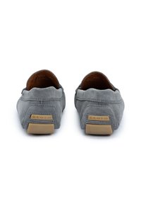 Grå ruskinds slip-on sko med en rund form, læderfoder og kontrasterende tan gummisåler. Har prægede mærker på hælen.