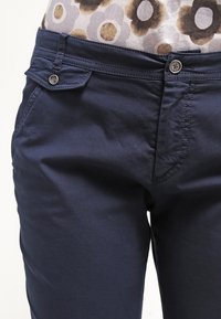 Navyblå bomullsbukser med en mjuk textur, med en framknäppning och sidofickor, utformade för en åtsittande passform.