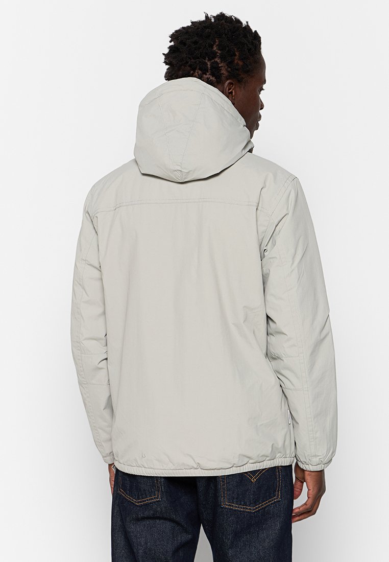 Veste à capuche gris clair avec une texture lisse et mate, dotée d'une capuche à cordon de serrage, de poignets élastiques et d'une coupe à la taille.