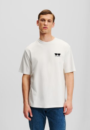 Witte katoenen T-shirt met korte mouwen, ronde halslijn en zwart zonnebril logo op de linkerkant van de borst. Gemaakt in combinatie met blauwe denim jeans.