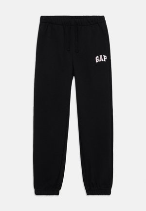 Črne trenirke z elastičnim pasom in manšetami. Na levi strani ima svetlo roza logotip "GAP". Gladka tekstura tkanine.