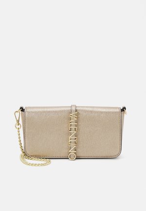 Béžová metalická kabelka Valentino s zlatým řetízkem a vertikálním zlatým logem "Valentino" na přední klopě, umístěná na bílém pozadí.