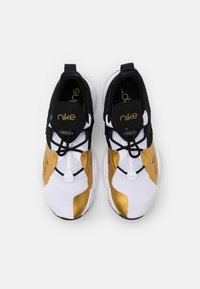 Nike sneakers met een witte ademende mesh bovenkant, gouden accenten, zwarte veters en een gevoerde zool voor ondersteuning en comfort.