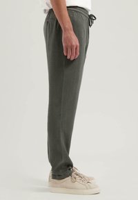 Lette, mørkegrønne joggebukser med elastisk linning og snøring. Har sidelommer og rett ben-design.