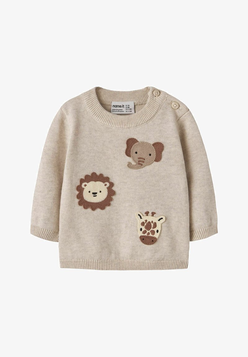 Pull beige pour bébé avec des visages de lion, d’éléphant et de girafe tricotés sur le devant et deux boutons aux épaules pour la fermeture.