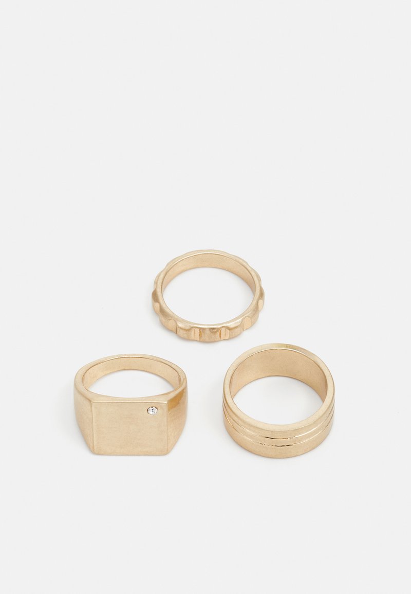 Tre guld ringe: en firkantet ring med en lille sten, et struktureret bånd med ribber, og et glat, poleret bånd med to riller.