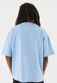 Camiseta de gran tamaño de color azul claro, hecha de una tela suave, con un corte holgado y mangas cortas, que presenta una textura suave y un diseño sencillo.
